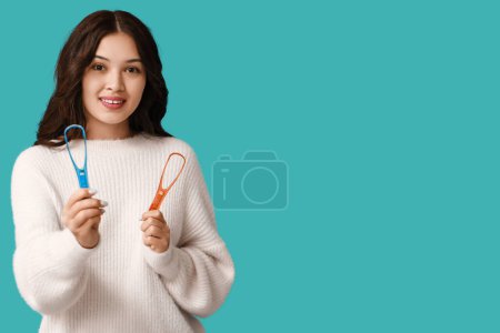 Téléchargez les photos : Jeune femme asiatique avec grattoirs de langue sur fond bleu - en image libre de droit