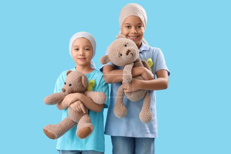 Photo for Cute little children after chemotherapy with yellow ribbons and teddy bears on blue background. Childhood cancer awareness concept - Royalty Free Image