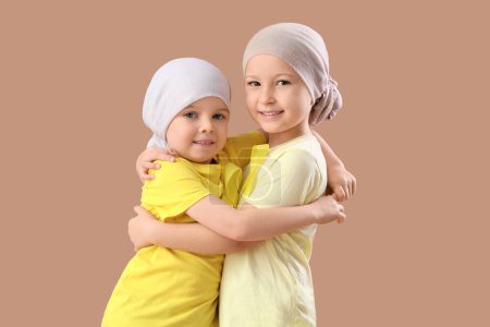Téléchargez les photos : Petites filles mignonnes après la chimiothérapie avec des rubans jaunes sur fond brun. Concept de sensibilisation au cancer chez l'enfant - en image libre de droit