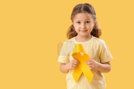 Téléchargez les photos : Petite fille mignonne avec ruban jaune sur fond de couleur. Concept de sensibilisation au cancer chez l'enfant - en image libre de droit