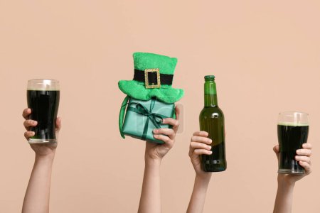 Photo for Hands with beer, gift and party decor on beige background. St. Patrick's Day celebration - Royalty Free Image