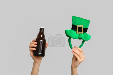 Photo for Hands with beer and party decor in shape of leprechaun's hat on light background. St. Patrick's Day celebration - Royalty Free Image