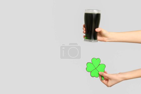 Photo for Hands with beer and shamrock on light background. St. Patrick's Day celebration - Royalty Free Image