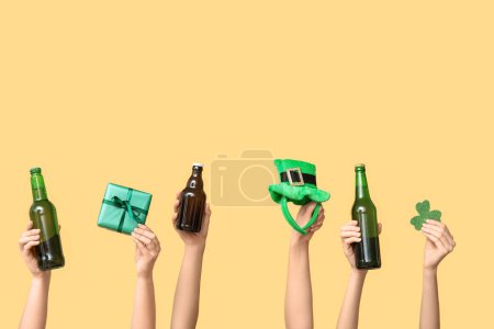 Photo for Hands with beer, gift and party decor on yellow background. St. Patrick's Day celebration - Royalty Free Image