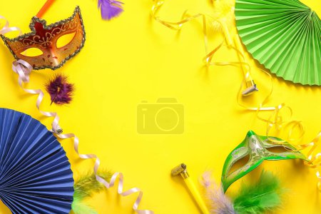Téléchargez les photos : Cadre fait de masques de carnaval avec cornes de fête et décor pour la célébration de Mardi Gras sur fond jaune - en image libre de droit