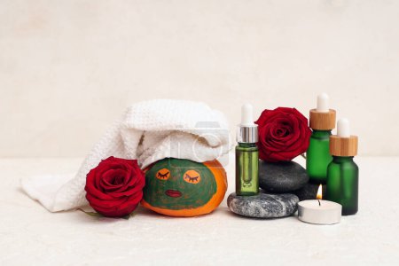 Foto de Calabaza con cara dibujada, suministros de spa, rosas y máscara de arcilla sobre fondo claro - Imagen libre de derechos