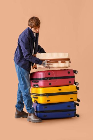 Foto de Joven con un montón de maletas en el fondo de color - Imagen libre de derechos