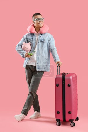 Foto de Joven con cóctel, alcancía y maleta sobre fondo rosa - Imagen libre de derechos