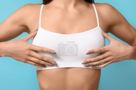 Téléchargez les photos : Jeune femme vérifiant son sein sur fond bleu - en image libre de droit
