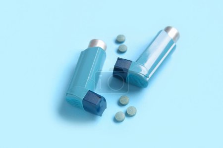 Téléchargez les photos : Inhalateurs d'asthme avec des pilules sur fond bleu - en image libre de droit
