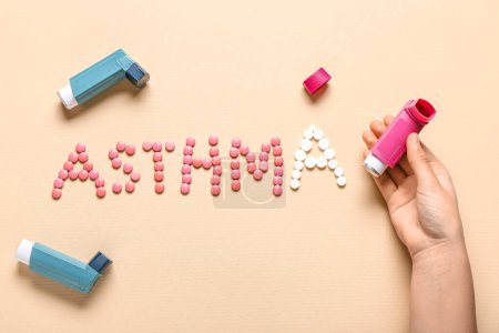 Téléchargez les photos : Main d'enfant avec inhalateurs et mot ASTHMA fait de pilules sur fond beige - en image libre de droit
