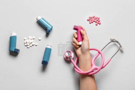 Téléchargez les photos : Main d'enfant avec inhalateurs d'asthme, pilules et stéthoscope sur fond blanc - en image libre de droit