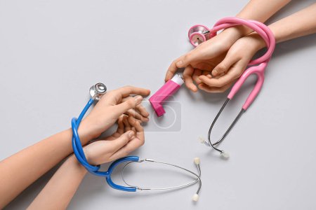 Photo for Child's hands with asthma inhaler and stethoscopes on white background - Royalty Free Image