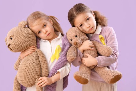 Photo for Cute little girls with yellow ribbons and teddy bears on lilac background. Childhood cancer awareness concept - Royalty Free Image