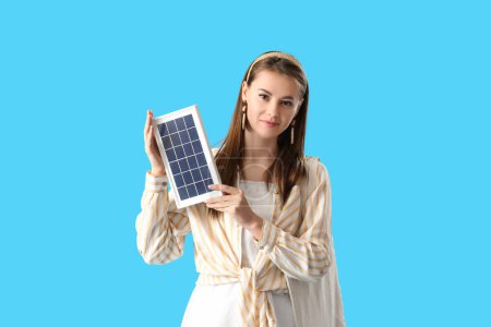 Foto de Mujer bastante joven con panel solar portátil sobre fondo azul - Imagen libre de derechos
