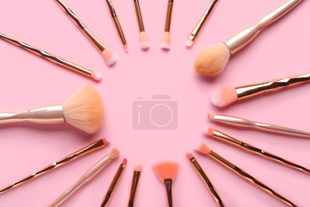 Téléchargez les photos : Cadre composé de différentes pinceaux de maquillage sur fond rose - en image libre de droit