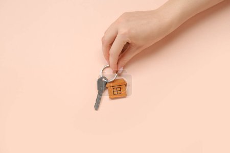 Téléchargez les photos : Main féminine tenant la clé avec bibelot en forme de maison sur fond rose. Concept d'achat immobilier - en image libre de droit