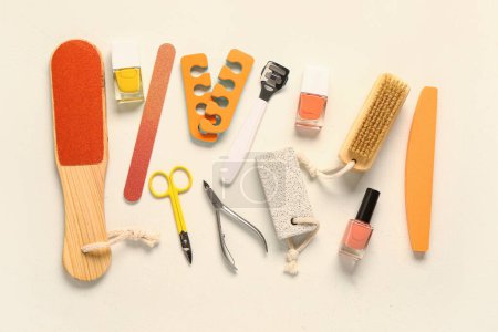 Foto de Set de herramientas profesionales para pedicura con esmaltes de uñas sobre fondo beige - Imagen libre de derechos