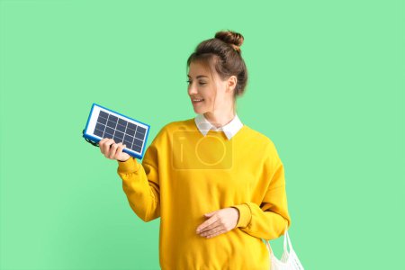 Foto de Mujer bastante joven con panel solar portátil sobre fondo verde - Imagen libre de derechos