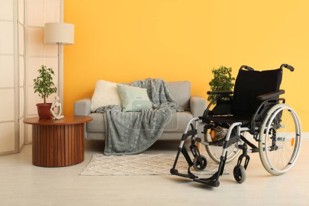 Foto de Moderna silla de ruedas vacía en sala de estar cerca de la pared amarilla - Imagen libre de derechos