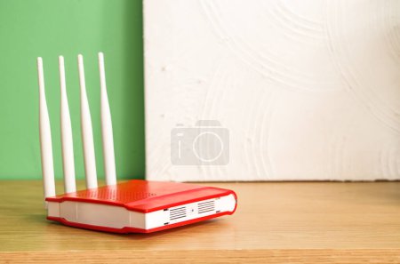 Modern wi-fi router and painting on shelf near green wall, closeup