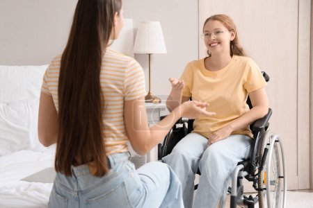 Foto de Joven pelirroja en silla de ruedas hablando con su amiga en casa - Imagen libre de derechos