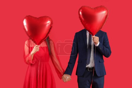 Téléchargez les photos : Couple with heart-shaped air balloons for Valentine's day on red background - en image libre de droit