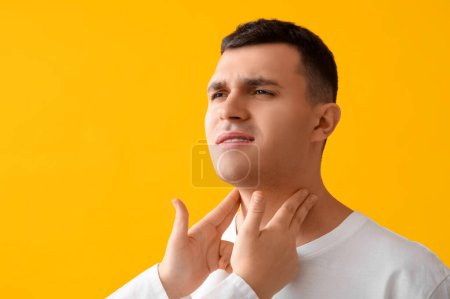Photo for Endocrinologist examining thyroid gland of young man on yellow background, closeup - Royalty Free Image