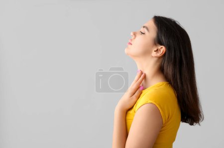 Photo for Young woman with thyroid gland problem on grey background - Royalty Free Image