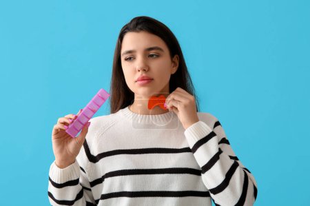 Photo for Young woman with paper thyroid gland and pill box on blue background - Royalty Free Image