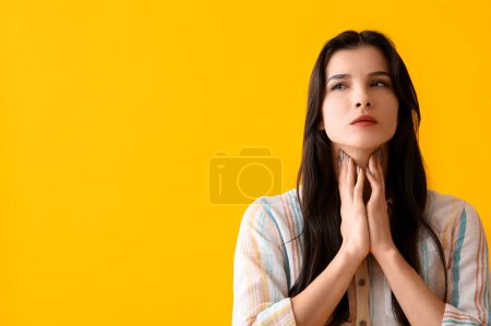 Photo for Young woman with thyroid gland problem on yellow background - Royalty Free Image