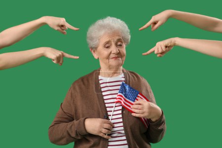 Menschen zeigen auf eine ältere Frau mit US-Flagge auf grünem Hintergrund. Anschuldigungskonzept