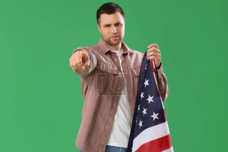 Junger Mann mit USA-Fahne zeigt auf den Betrachter auf grünem Hintergrund. Anschuldigungskonzept