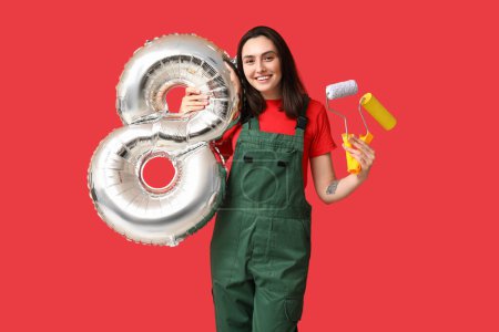 Foto de Retrato de joven pintora con rodillos de pintura y globo en forma de figura 8 sobre fondo rojo. Día Internacional de la Mujer - Imagen libre de derechos