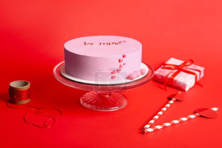 Photo for Stand with pink bento cake, gift box and straws on red background. Valentine's Day celebration - Royalty Free Image
