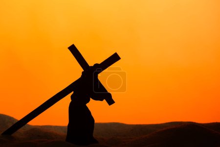 Photo for Jesus carrying wooden cross on sand against orange background. Good Friday concept - Royalty Free Image