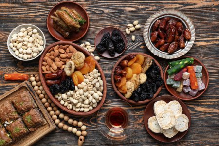 Komposition mit traditionellen orientalischen Süßigkeiten, Tee und Tasbih für den Ramadan auf Holzgrund