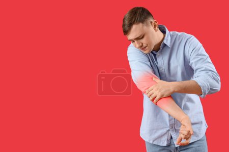 Photo for Young man feeling pain in elbow on red background - Royalty Free Image