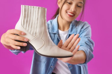 Photo for Young Asian seller with boot on purple background, closeup - Royalty Free Image