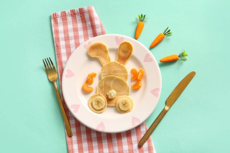 Téléchargez les photos : Crêpes de lapin de Pâques drôles avec banane et mandarine sur fond turquoise - en image libre de droit