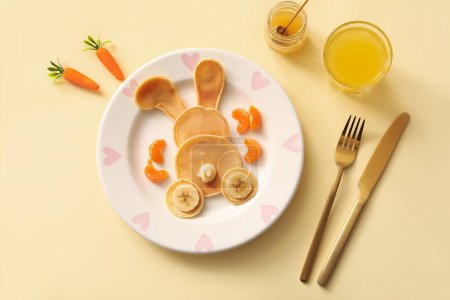 Téléchargez les photos : Crêpes de lapin de Pâques drôles avec banane et verre de jus d'orange sur fond jaune - en image libre de droit