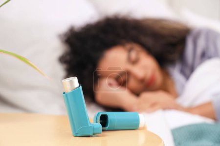 Téléchargez les photos : Inhalateur d'asthme sur la table de la femme endormie dans la chambre, gros plan - en image libre de droit