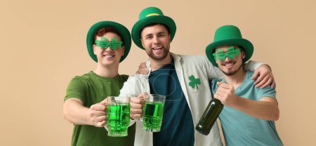 Photo for Happy young men in leprechaun's hats and with green beer on beige background. St. Patrick's Day celebration - Royalty Free Image