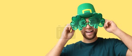 Photo for Happy young man wearing leprechaun's hat and party glasses on yellow background with space for text. St. Patrick's Day celebration - Royalty Free Image