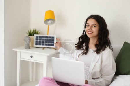 Foto de Chica adolescente con portátil y panel solar portátil en el dormitorio - Imagen libre de derechos