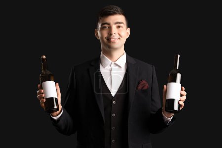 Photo for Young sommelier with bottles of wine on black background - Royalty Free Image