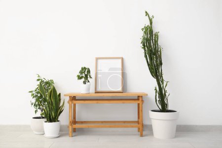 Foto de Gran cactus con pintura, plantas de interior y mesa cerca de la pared blanca en la habitación - Imagen libre de derechos