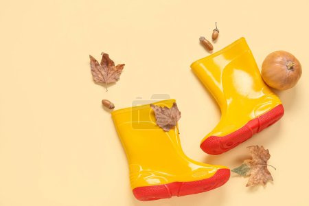 Foto de Botas de goma amarillas con calabaza, bellotas y hojas de otoño sobre fondo de color - Imagen libre de derechos