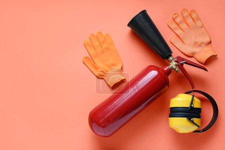 Foto de Extintor de incendios, protectores auditivos y guantes sobre fondo rojo - Imagen libre de derechos
