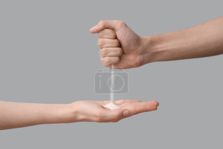 Photo for Sand pouring from male hand to female on grey background. Time concept - Royalty Free Image